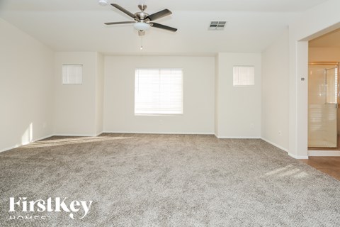 A spacious room with a ceiling fan and carpeted floor.