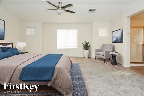 A bedroom with a bed, a chair, and a ceiling fan.