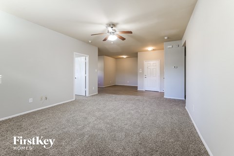 a spacious living room with carpet and a ceiling fan