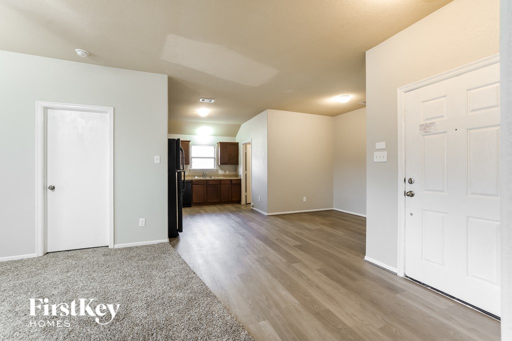 a living room and kitchen with white doors and wood flooring