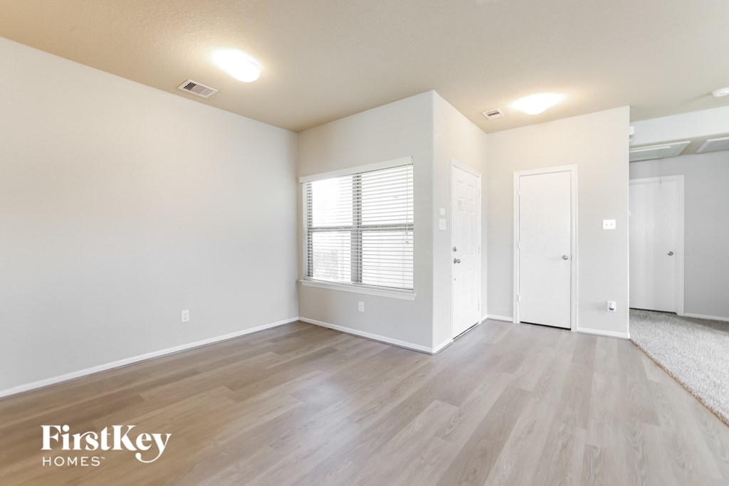 a spacious living room with white walls and wood flooring