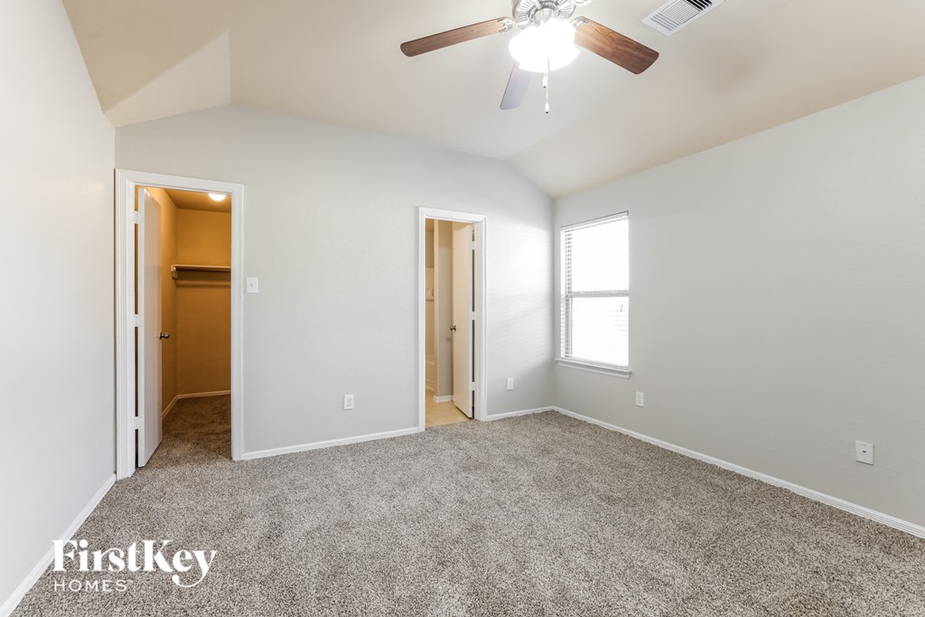 a spacious living room with carpet and a ceiling fan