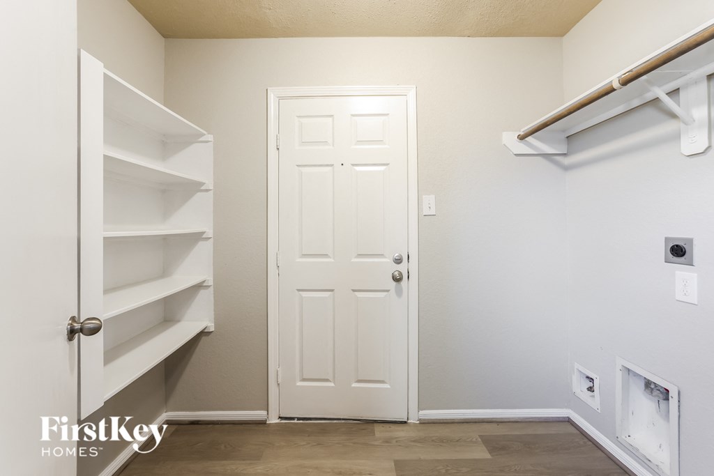 a walk in closet with a white door and shelves and a door to a closet