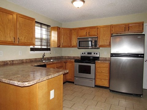 A kitchen with wooden cabinets and a granite counter top.