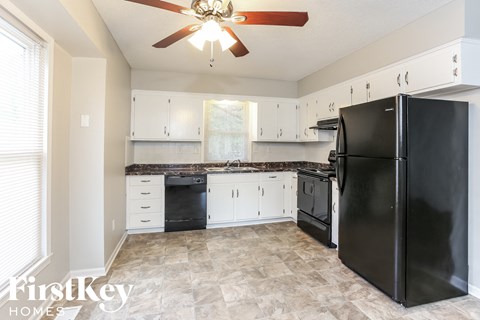 A kitchen with a black refrigerator and a ceiling fan.