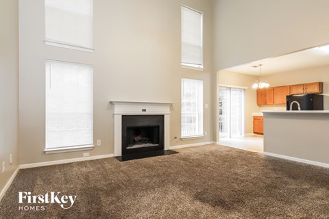 A living room with a fireplace and a carpet on the floor.