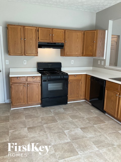 A kitchen with wooden cabinets and a black stove top oven.