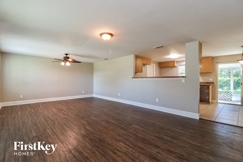 A spacious room with wooden flooring and a ceiling fan.