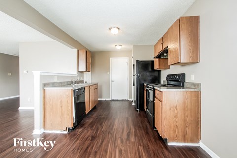a kitchen with wood floors and wooden cabinets and black appliances