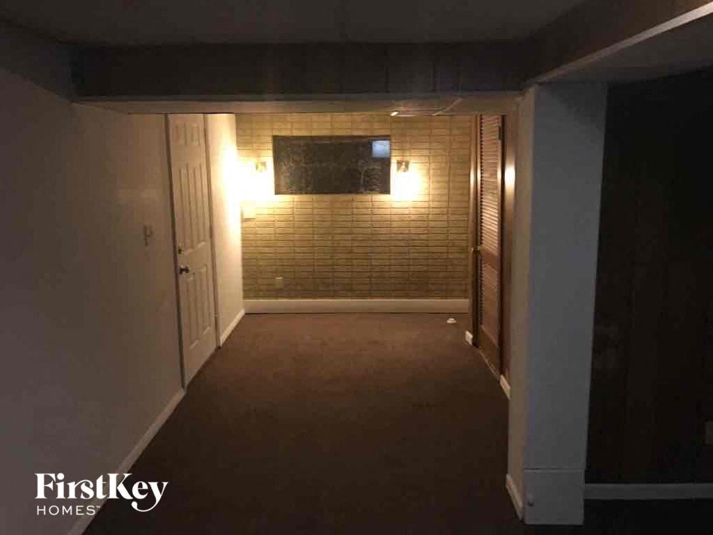 A dark hallway with a light on the wall and a door on the left.