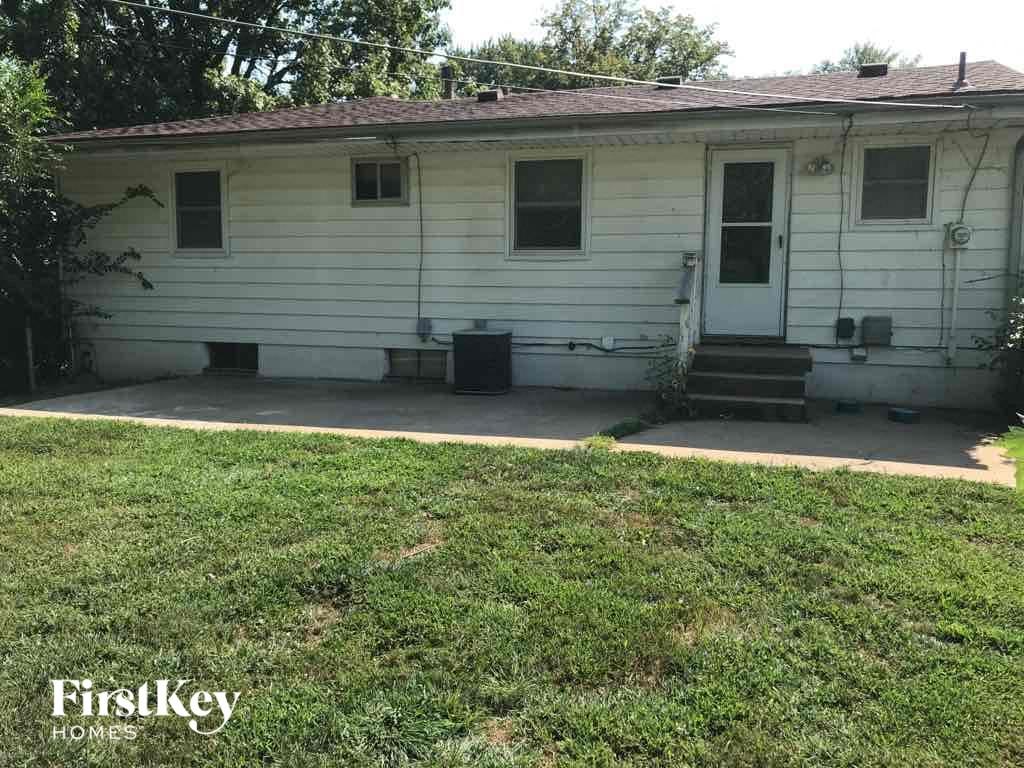 A white house with a brown roof and a porch.
