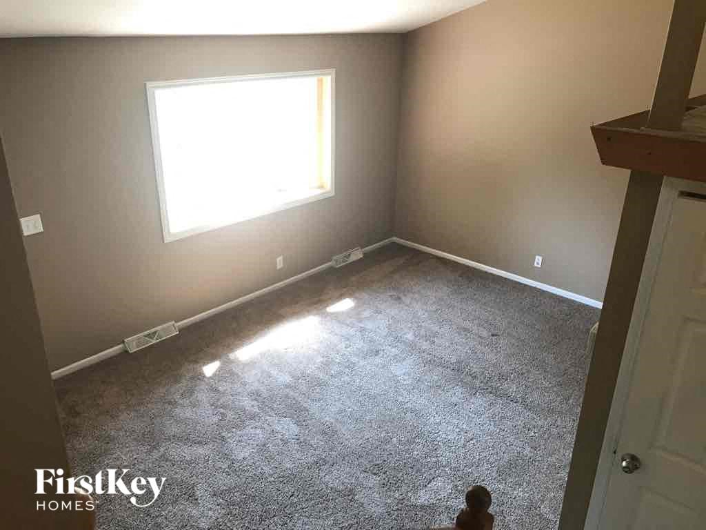 A room with a carpeted floor and a window letting in sunlight.