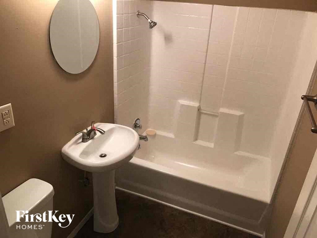 A white sink and toilet in a bathroom with a white tub.