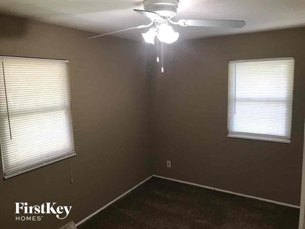 A room with a ceiling fan and two windows.