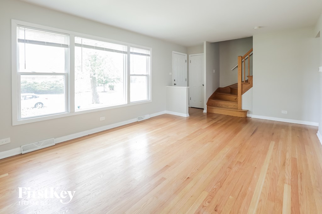 an empty living room with a hard wood floor and large windows