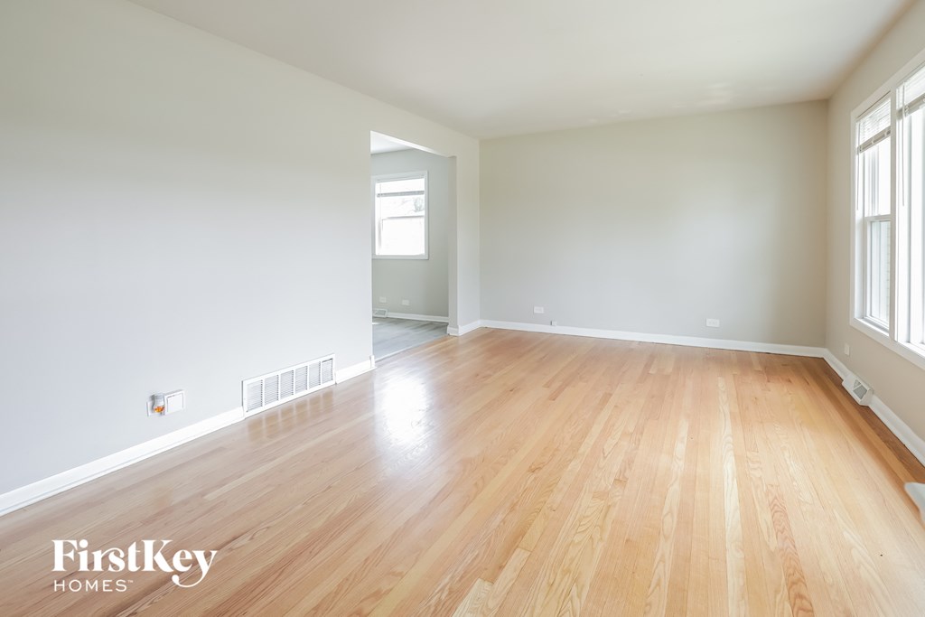 an empty living room with wood floors and white walls