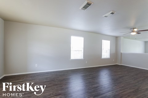 a living room with wood floors and white walls and a ceiling fan
