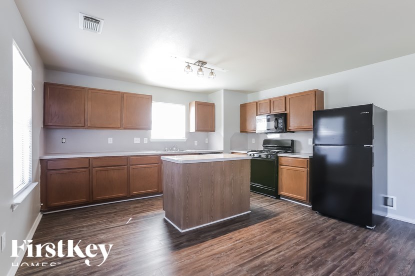 A kitchen with wooden cabinets and a black refrigerator.