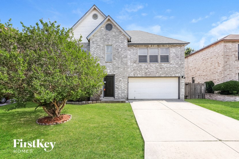 A house with a garage and a tree in front of it.