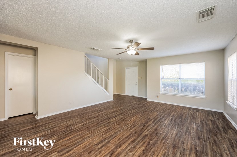 A spacious room with wooden flooring and a ceiling fan.