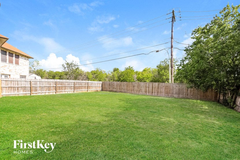A backyard with a wooden fence and a grassy area.