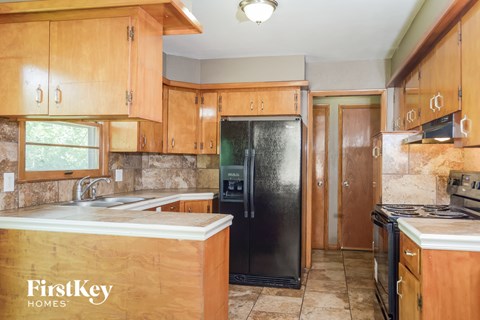 a kitchen with wooden cabinets and a black refrigerator