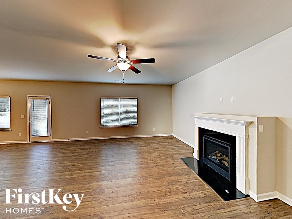 A spacious room with a fireplace and a ceiling fan.