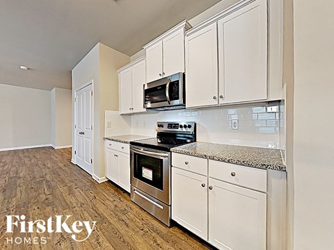 A kitchen with white cabinets and a stove top oven.