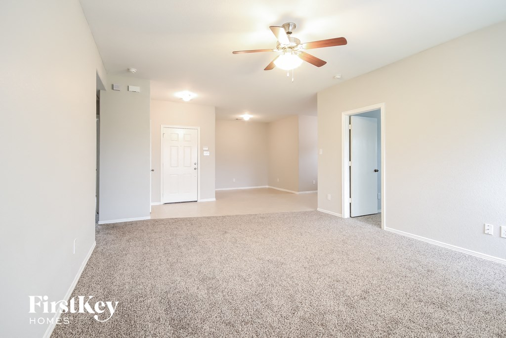 a spacious living room with carpet and a ceiling fan