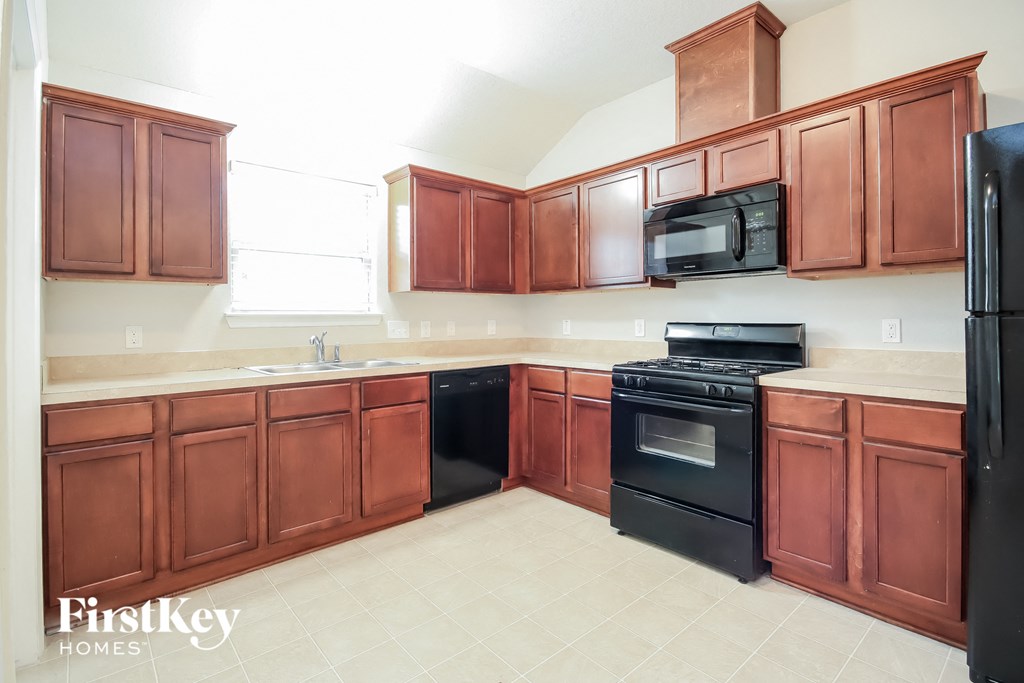 a large kitchen with wooden cabinets and black appliances