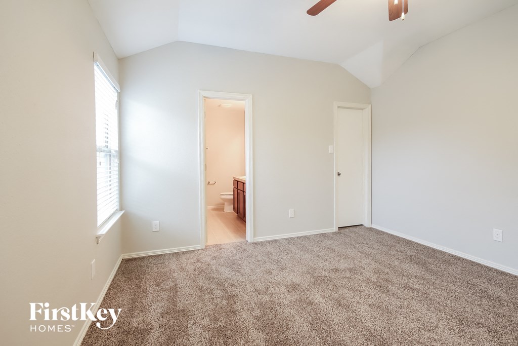 a bedroom with a carpeted floor and a door to a bathroom