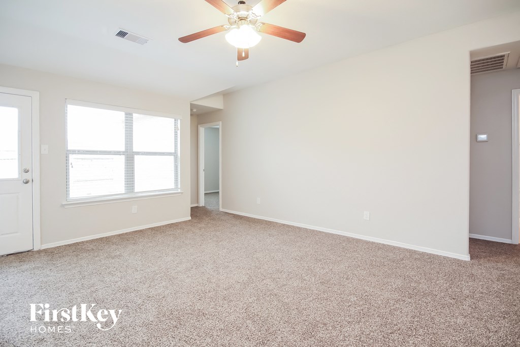 an empty living room with a ceiling fan and a window