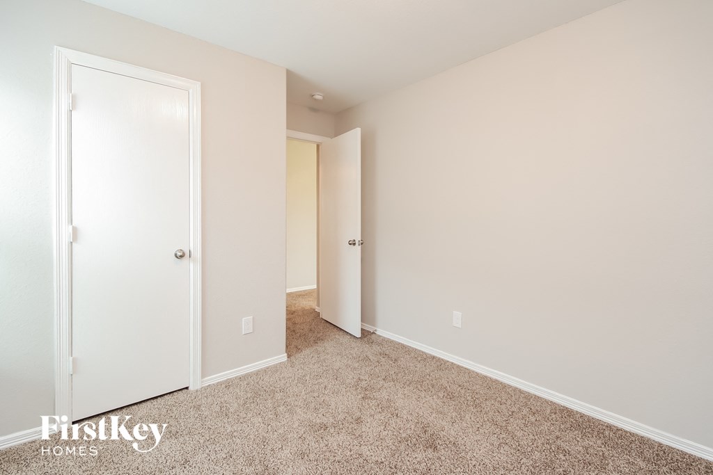 a bedroom with a door to a closet and a carpeted floor