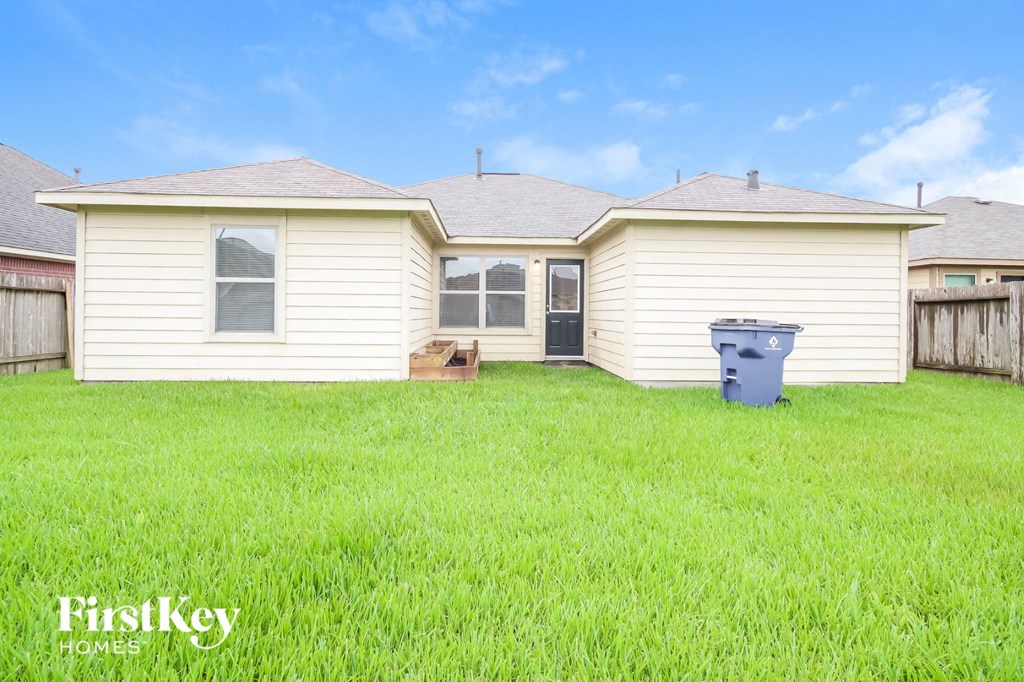 a backyard with a house and a trash can