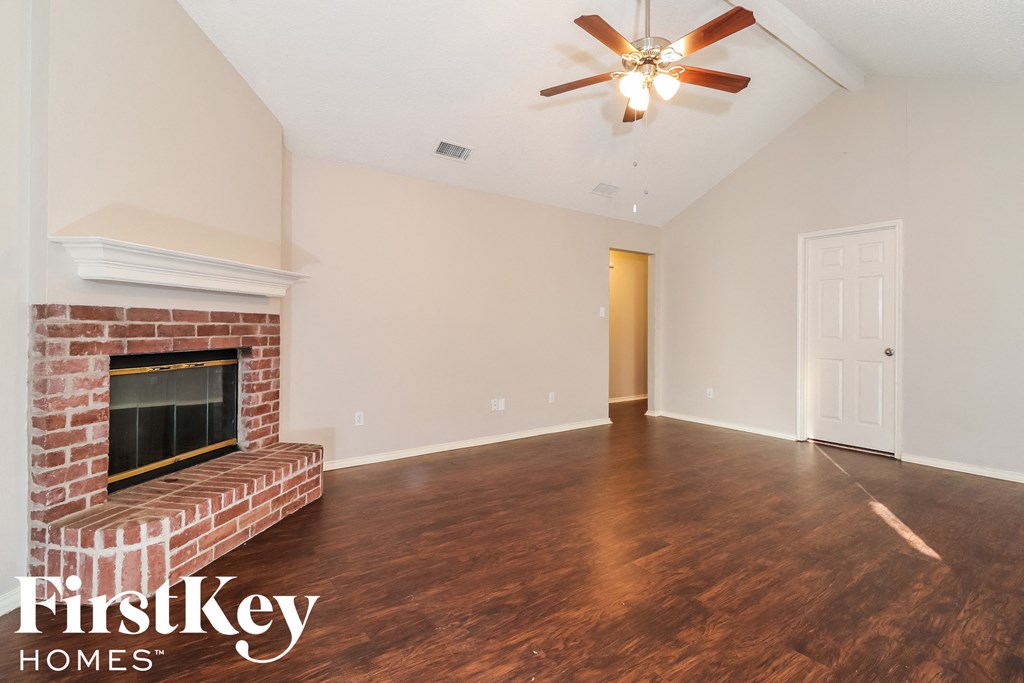 A room with a brick fireplace and wooden floors.