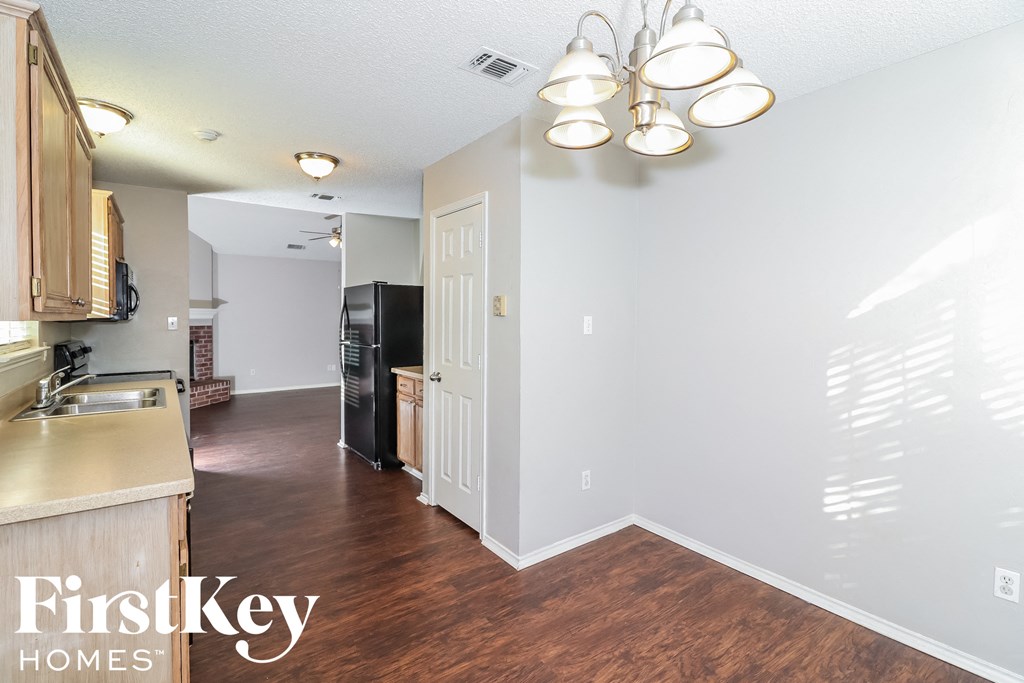 A kitchen area with a refrigerator, sink, and cabinets.