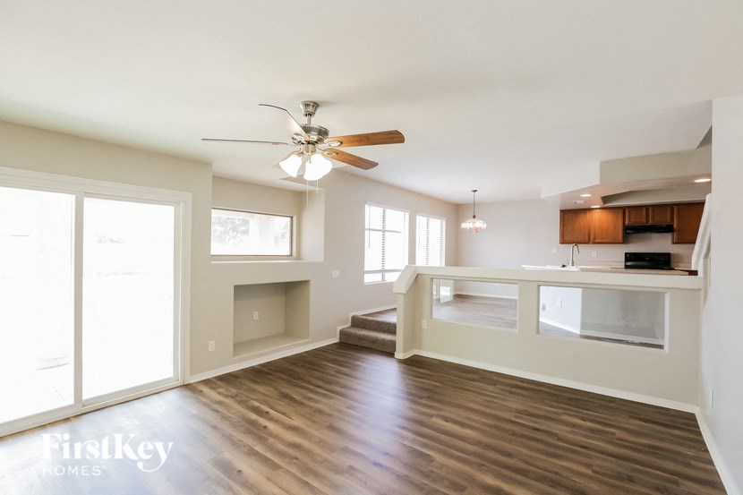 a living room with a kitchen and a ceiling fan