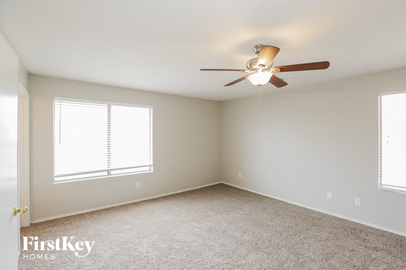 a bedroom with a ceiling fan and two windows