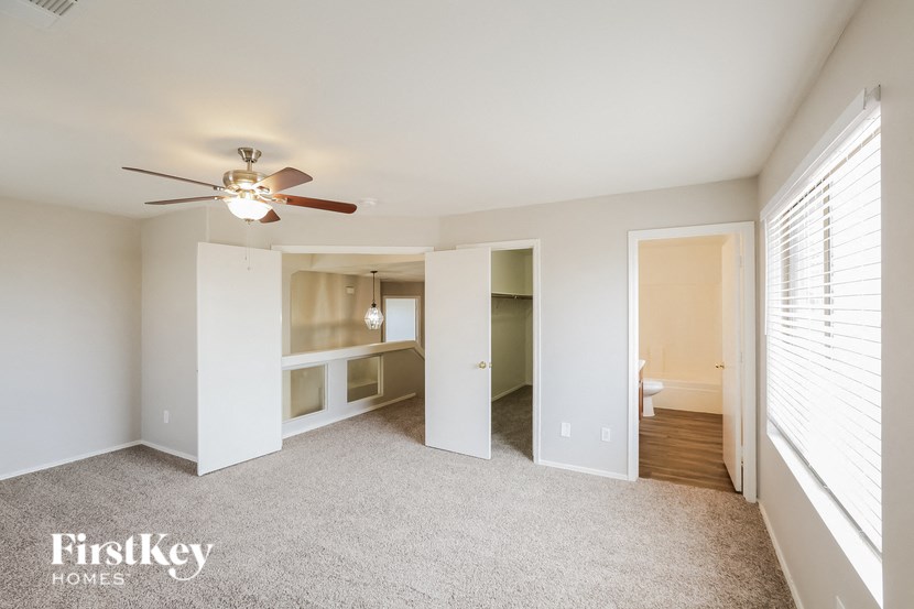 an empty living room with a ceiling fan and a closet