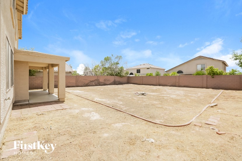 an empty yard with a hose on the ground in front of a house