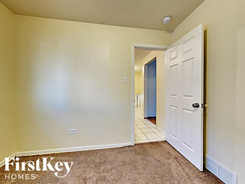 a bedroom with a white door and a hallway to a closet