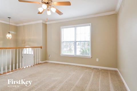 A spacious room with a ceiling fan and a window with blinds.