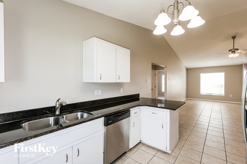 A kitchen with white cabinets and black countertops.