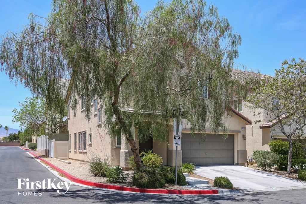 a house with a driveway and a tree in front of it