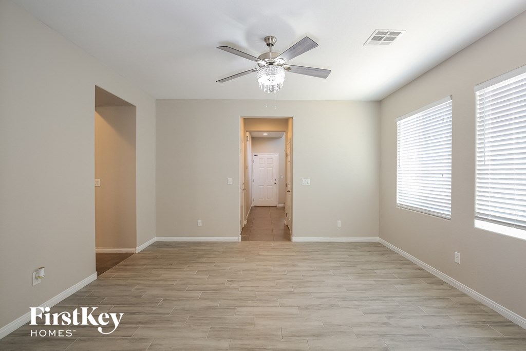 an empty living room with a ceiling fan and a hallway to a closet