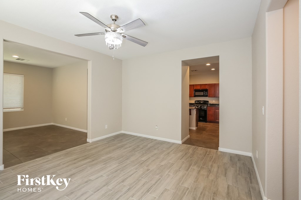 an empty living room with a ceiling fan and wood flooring