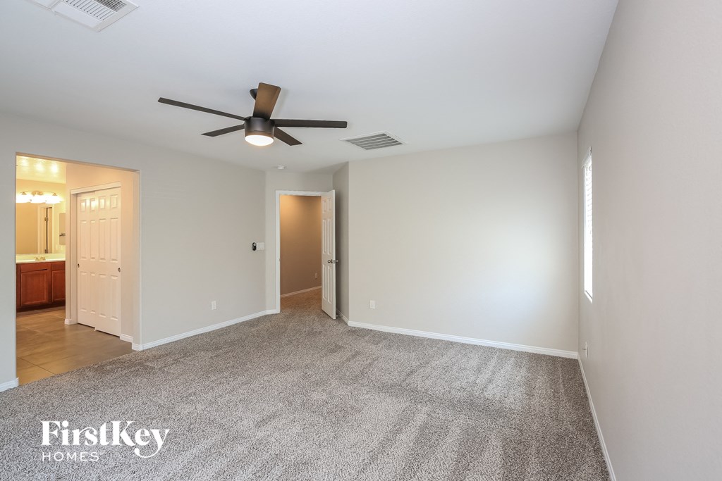 an empty living room with a ceiling fan and a rug