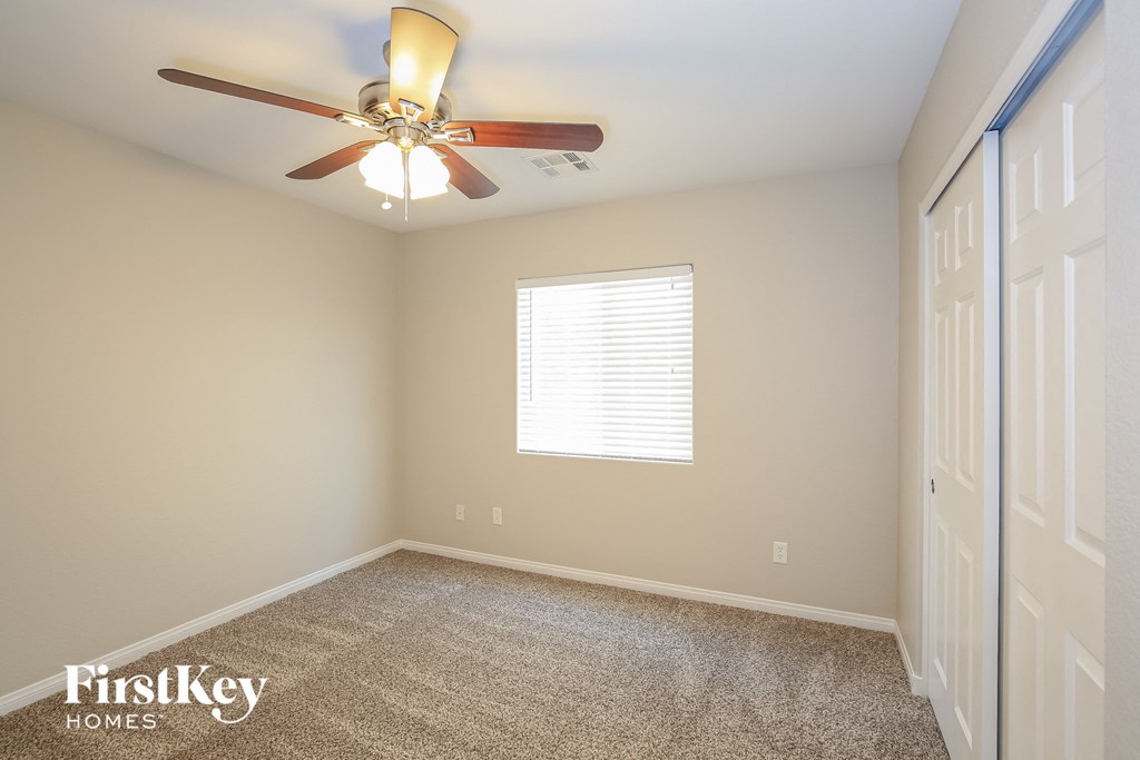 a bedroom with a ceiling fan and a door to a closet