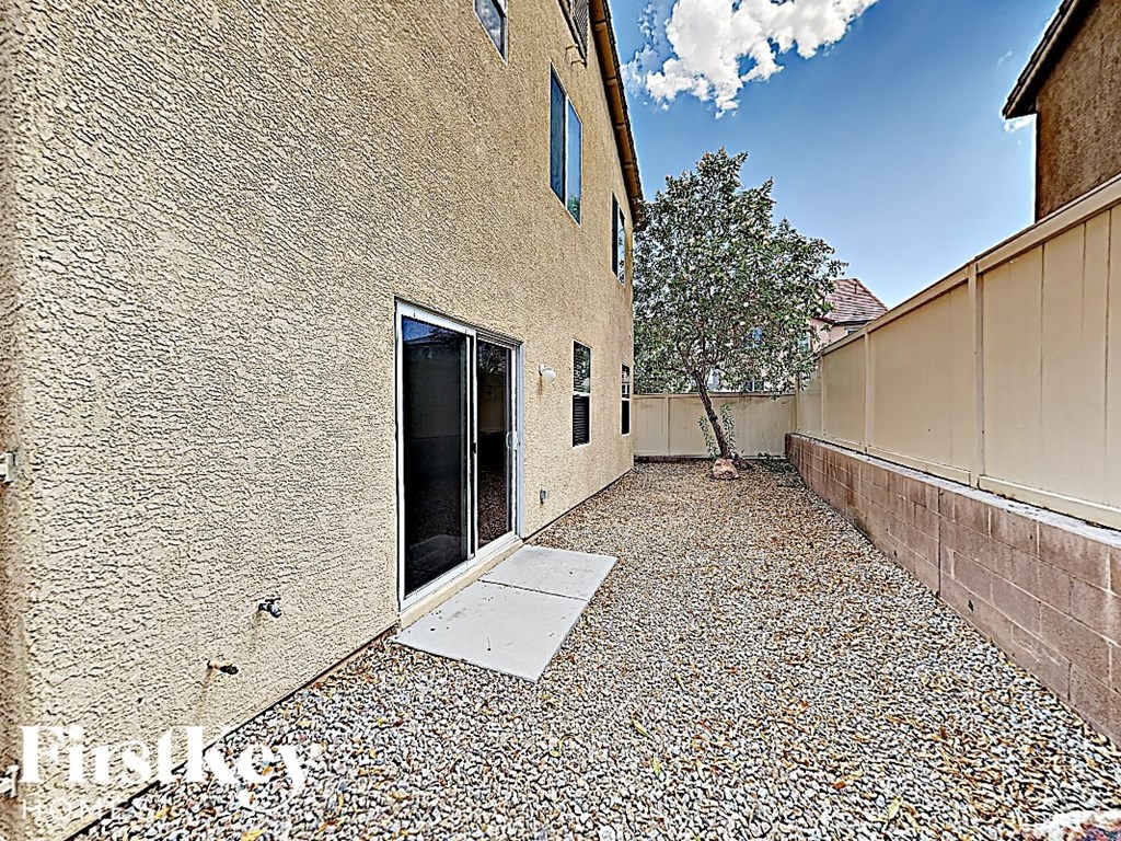 A gravel backyard with a building and a tree.