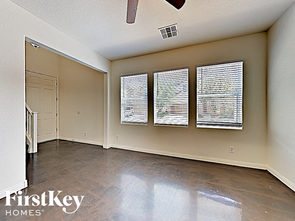 A room with a ceiling fan and three windows.